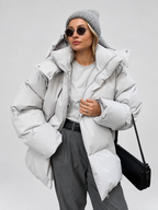 Women's Oversized Hooded Puffer Jacket with High Collar and Wide Quilting in Light Grey – Front View