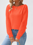 Women's round neck knitted jumper in Orange, seated view with open knit sleeves